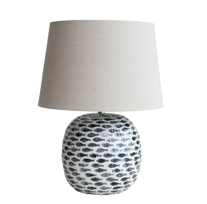 A ceramic table lamp with a round base featuring a black and white tear-shaped pattern, topped with a plain off-white lampshade.